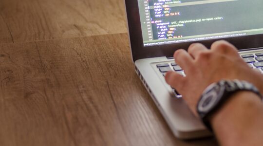Close-up of a person coding on a laptop, showcasing web development and programming concepts.