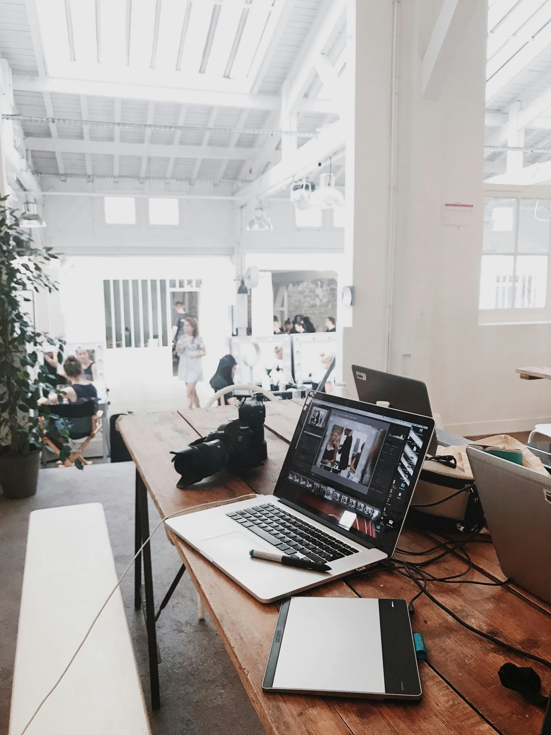 Home A bright, modern workspace featuring laptops, a camera, and a drawing tablet in an indoor office.